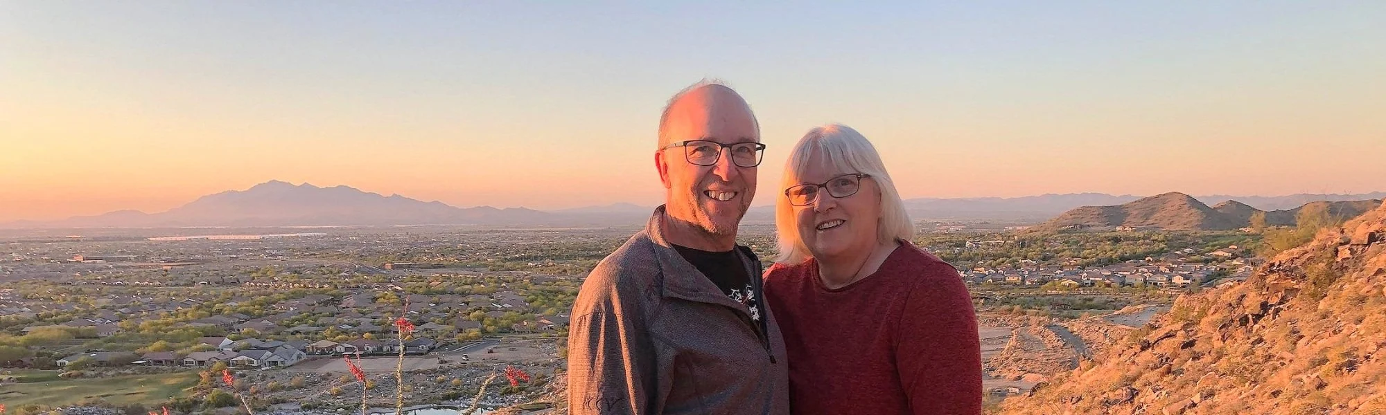 Jon and Jude standing together on a hillside at sunset